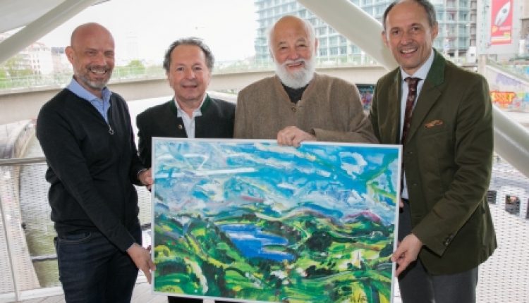 Vier Männer stehen in einem Haus zusammen, halten ein buntes Landschaftsgemälde in der Hand und lächeln in die Kamera.