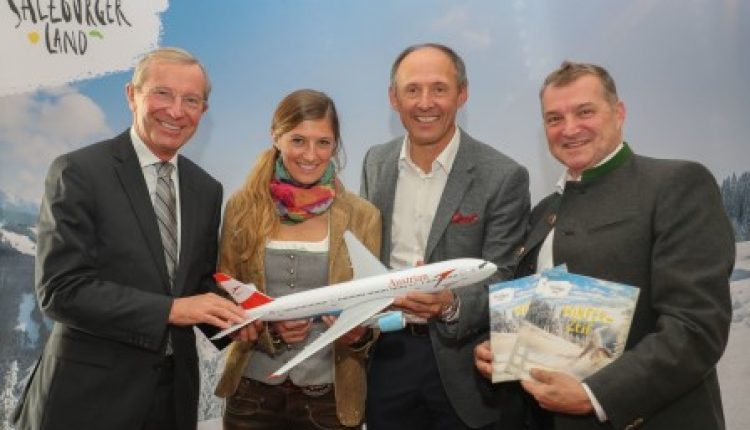 Vier Personen, die lächelnd ein Modellflugzeug und Broschüren vor einer Kulisse der Region Salzburg halten.