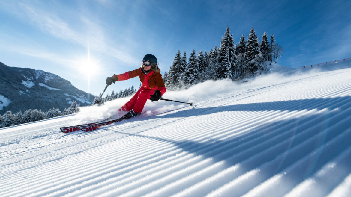 Ein Skifahrer, der auf einer präparierten Piste in den österreichischen Bergen eine Kurve zieht.